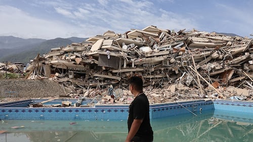 A person walking in front of debris from an earthquake