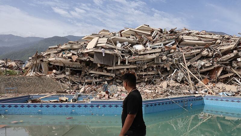 A person walking in front of debris from an earthquake