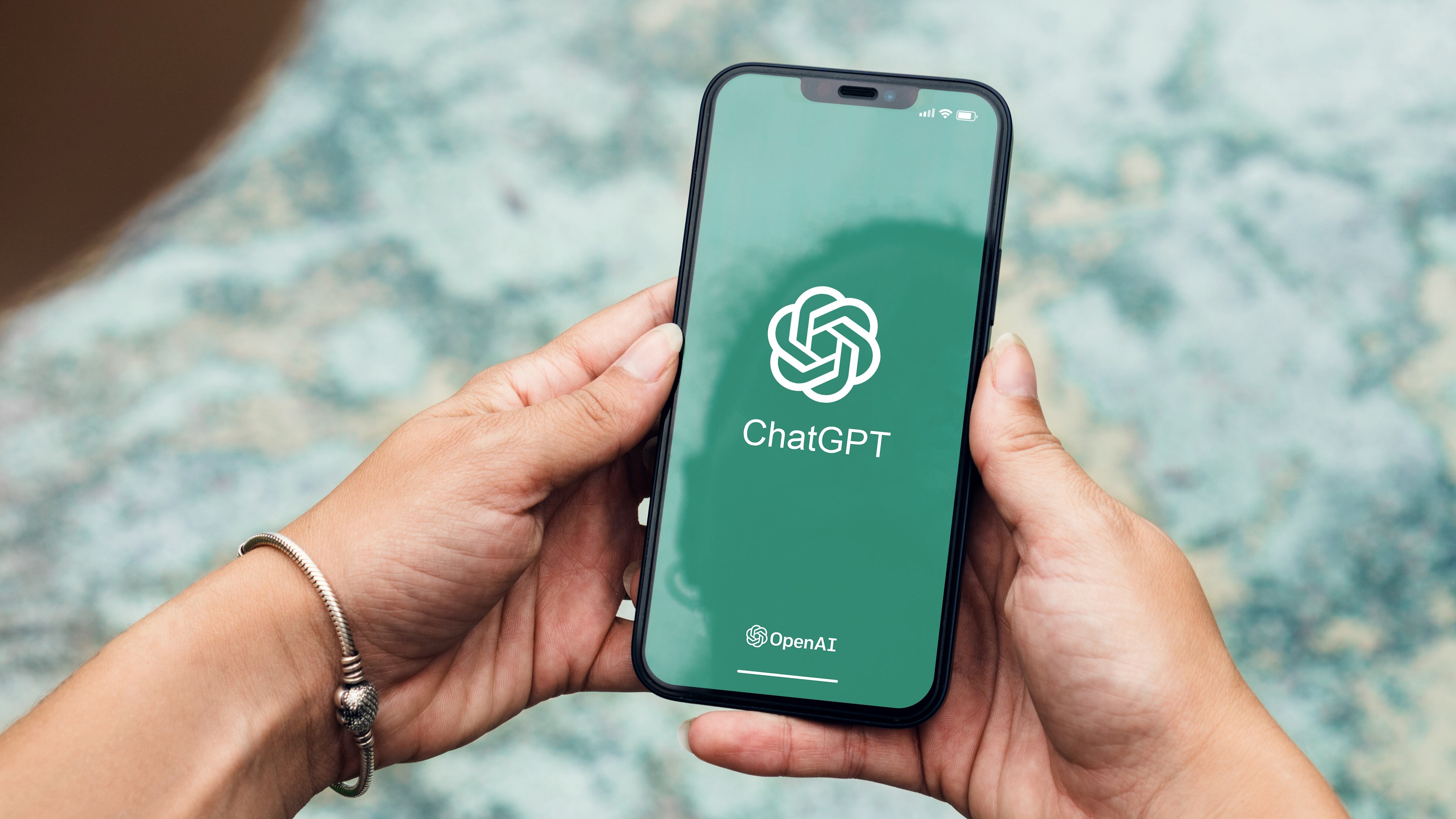 Girl in the park holding a smartphone with ChatGPT artificial intelligence chatbot app on the screen.